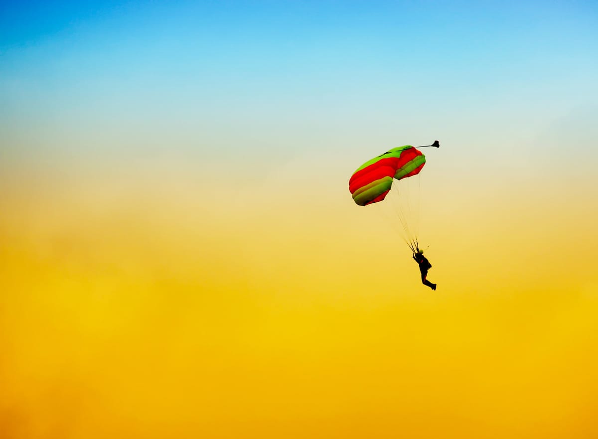 Student skydiver flying solo under parachute during skydiving course at sunset.