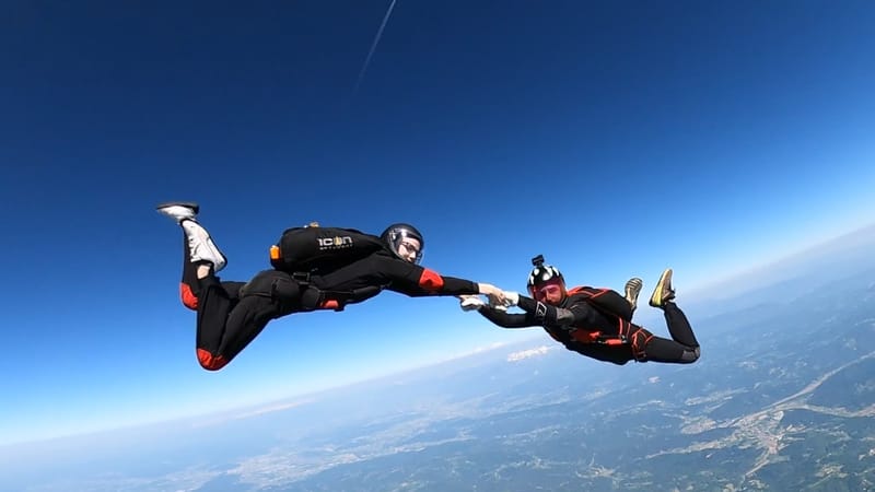 USPA Coach and student practicing free fall maneuvers while holding grips mid-air